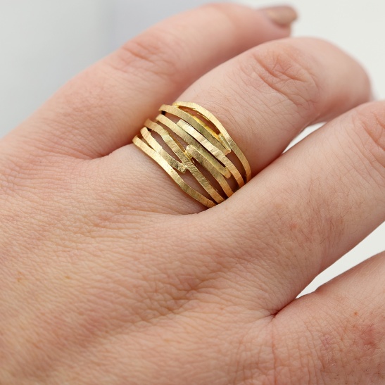 nami_gouden_ring_met_lijnen_en_openingen_aan_de_vinger_gedragen